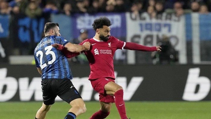 Atalantas Sead Kolasinac, left, fights for the ball with Liverpools Mohamed Salah during the Europa League quarterfinal, second leg, soccer match between Atalanta and Liverpool at the Stadio di Bergamo, in Bergamo, Italy, Thursday, April 18, 2024. (AP Photo/Antonio Calanni)