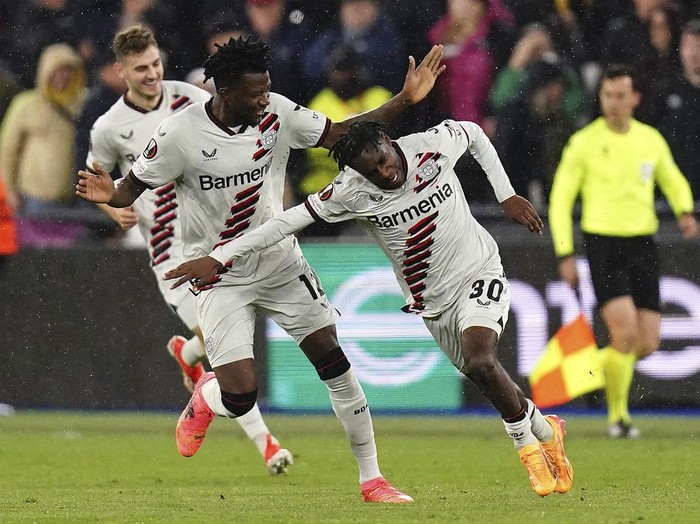 Leverkusen's Jeremie Frimpong, right, celebrates after scoring his side's opening goal during the Europa League quarterfinal second leg soccer match between West Ham and Bayer 04 Leverkusen in London, Thursday, April 18, 2024. John Walton/PA via AP)