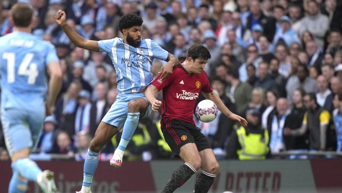 Manchester Uniteds Harry Maguire, right, challenges for the ball with Coventry Citys Ellis Reco Simms during the English FA Cup semifinal soccer match between Coventry City and Manchester United at Wembley stadium in London, Sunday, April 21, 2024. (AP Photo/Alastair Grant)