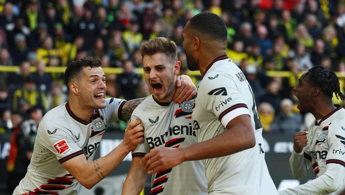 Soccer Football - Bundesliga - Borussia Dortmund v Bayer Leverkusen - Signal Iduna Park, Dortmund, Germany - April 21, 2024 Bayer Leverkusens Josip Stanisic celebrates scoring their first goal with Granit Xhaka and Jonathan Tah REUTERS/Thilo Schmuelgen DFL REGULATIONS PROHIBIT ANY USE OF PHOTOGRAPHS AS IMAGE SEQUENCES AND/OR QUASI-VIDEO.