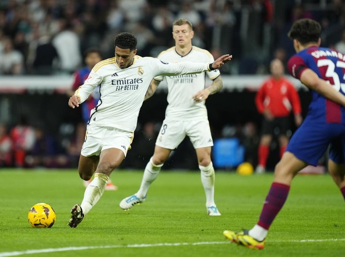 Real Madrid's Jude Bellingham shoots the ball during the Spanish La Liga soccer match between Real Madrid and Barcelona at the Santiago Bernabeu stadium in Madrid, Spain, Sunday, April 21, 2024. (AP Photo/Jose Breton)