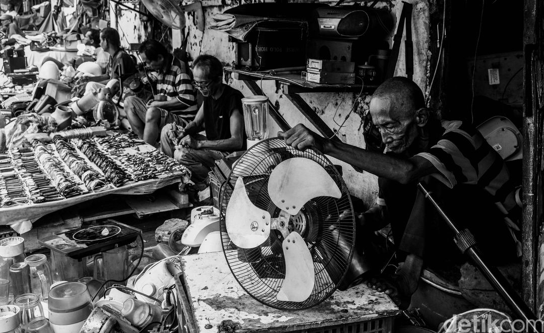 Pedagang mereparasi barang elektronik.