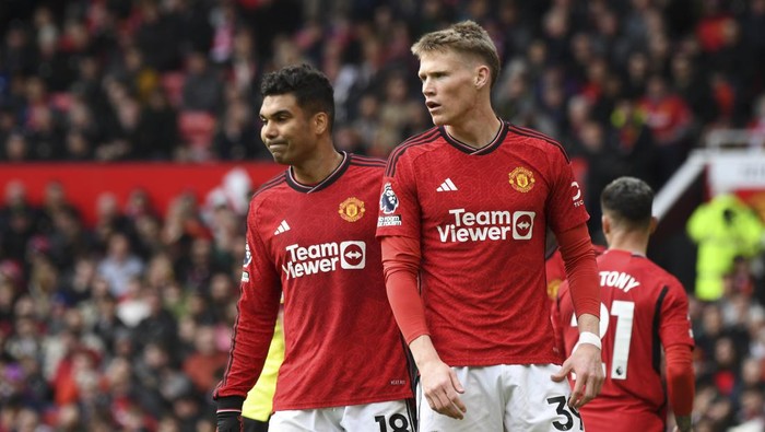 Manchester Uniteds Scott McTominay, right, and Casemiro react as referee John Brooks watches a VAR screen to check a possible penalty during the English Premier League soccer match between Manchester United and Burnley at Old Trafford stadium in Manchester, England, Saturday, April 27, 2024. (AP Photo/Rui Vieira)
