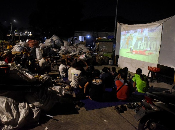 Warga menyaksikan pertandingan semifinal Piala Asia U-23 antara Timnas Indonesia melawan Uzbekistan melalui sebuah layar di lapak pemulung di kawasan Jalan Raya Tanjung Barat, Jakarta, Senin (29/4/2024). Antusiasme warga melalui kegiatan nobar (nonton bareng) dilakukan berbagai daerah untuk mendukung Timnas Indonesia U-23 yang berlaga dalam pertandingan tersebut. ANTARA FOTO/Indrianto Eko Suwarso/nym.