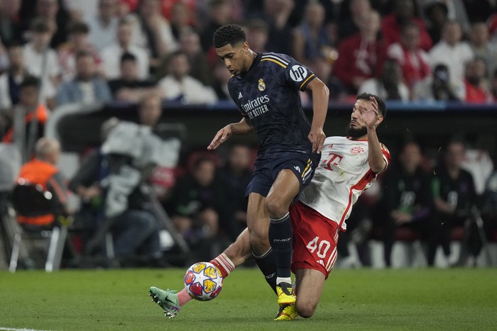 Real Madrids Jude Bellingham, left, is challenged by Bayerns Noussair Mazraoui during the Champions League semifinal first leg soccer match between Bayern Munich and Real Madrid at the Allianz Arena in Munich, Germany, Tuesday, April 30, 2024. (AP Photo/Matthias Schrader)