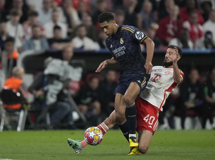 Real Madrid's Jude Bellingham, left, is challenged by Bayern's Noussair Mazraoui during the Champions League semifinal first leg soccer match between Bayern Munich and Real Madrid at the Allianz Arena in Munich, Germany, Tuesday, April 30, 2024. (AP Photo/Matthias Schrader)