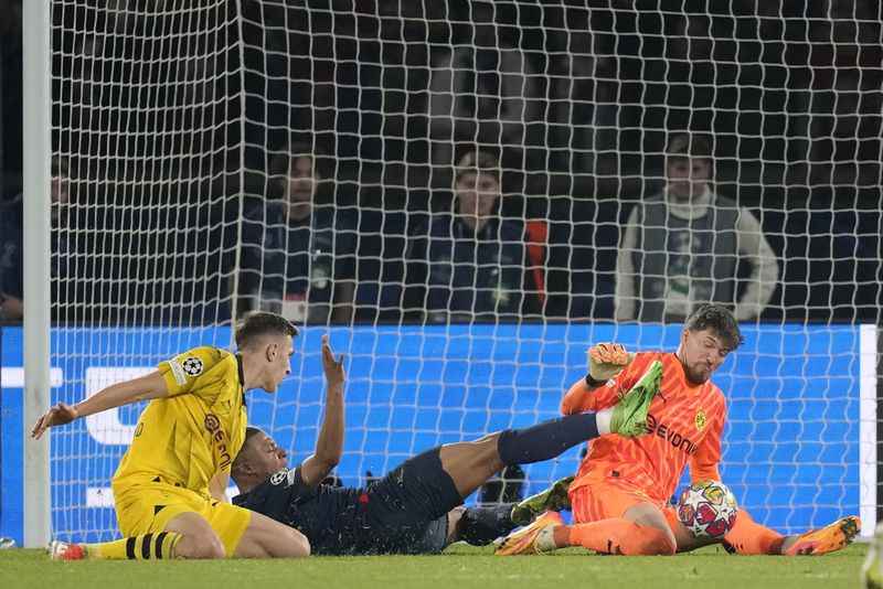 PSG's Kylian Mbappe, center, fails to score past Dortmund's goalkeeper Gregor Kobel, right, during the Champions League semifinal second leg soccer match between Paris Saint-Germain and Borussia Dortmund at the Parc des Princes stadium in Paris, France, Tuesday, May 7, 2024. (AP Photo/Christophe Ena)