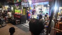 Sejumlah warga menyaksikan pertandingan babak playoff Olimpiade 2024 Paris antara Timnas Indonesia U-23 melawan Guinea di kawasan Stasiun Juanda, Jakarta, Kamis (9/5/2024).
