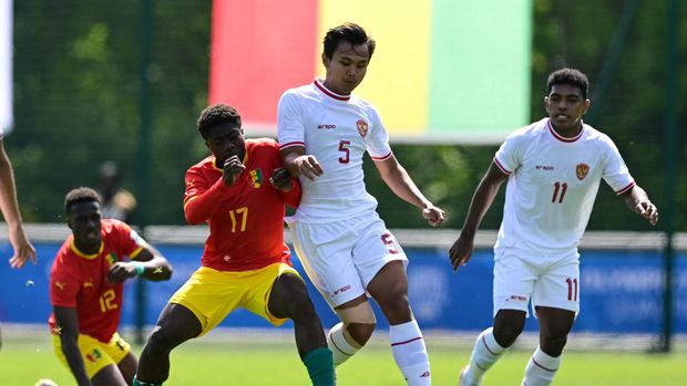 Indonesia's  defender#05 Komang Teguh (C) fights for the ball with Guinea's  midfielder #17 Issiaga Camara during the pre-Olympic play-off match between Indonesia and Guinea, for final spot in the mens Olympic football tournament at Paris 2024, in Clairefontaine-en-Yvelines, south of Paris, on May 9, 2024. (Photo by MIGUEL MEDINA / AFP)