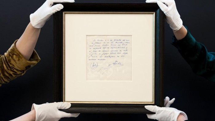 Kontrak Pertama Messi dengan Barcelona Dilelang, Ini Penampakannya A Bonhams staff member holds up a napkin on which a written commitment was made to then 13-year-old soccer player Lionel Messi from Argentina for a contract from FC Barcelona in December 2000 is on display at Bonhams in London, England, Wednesday, May 8, 2024 before it is offered at auction. ( Jordan Pettitt/PA via AP)