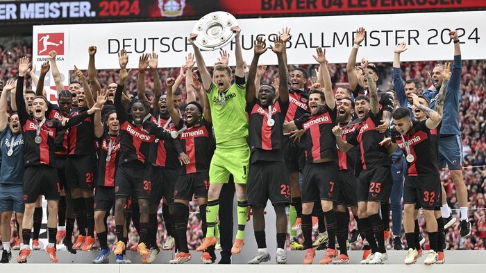 Leverkusens goalkeeper Lukas Hradecky, center, celebrates with the trophy as his team won the German Bundesliga soccer match between Bayer Leverkusen and FC Augsburg at the BayArena in Leverkusen, Germany, Saturday, May 18, 2024. Leverkusen completed one of the most remarkable league seasons in recent soccer history Saturday as the first team ever to finish an entire German Bundesliga campaign unbeaten. (Marius Becker/dpa via AP)