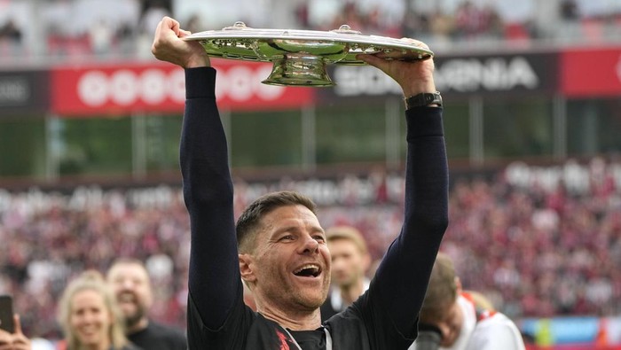 Leverkusens head coach Xabi Alonso celebrates with the trophy as his team won the German Bundesliga, after the German Bundesliga soccer match between Bayer Leverkusen and FC Augsburg at the BayArena in Leverkusen, Germany, Saturday, May 18, 2024. Bayer Leverkusen have won the Bundesliga title for the first time. It is the first team in Bundesliga history, that won the championship unbeaten for the whole season. (AP Photo/Martin Meissner)
