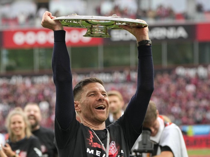 Leverkusen's head coach Xabi Alonso celebrates with the trophy as his team won the German Bundesliga, after the German Bundesliga soccer match between Bayer Leverkusen and FC Augsburg at the BayArena in Leverkusen, Germany, Saturday, May 18, 2024. Bayer Leverkusen have won the Bundesliga title for the first time. It is the first team in Bundesliga history, that won the championship unbeaten for the whole season. (AP Photo/Martin Meissner)