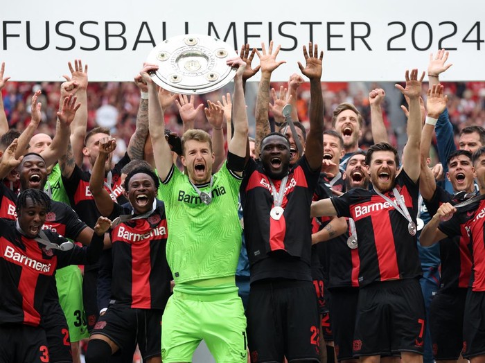 Soccer Football - Bundesliga - Bayer Leverkusen v FC Augsburg - BayArena, Leverkusen, Germany - May 18, 2024 Bayer Leverkusen's Lukas Hradecky lifts the trophy with Victor Boniface as they celebrate after winning the Bundesliga and going unbeaten REUTERS/Thilo Schmuelgen DFL REGULATIONS PROHIBIT ANY USE OF PHOTOGRAPHS AS IMAGE SEQUENCES AND/OR QUASI-VIDEO.