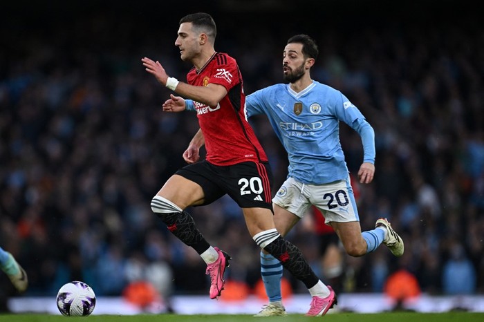 Manchester Uniteds Portuguese defender #20 Diogo Dalot (L) runs away from Manchester Citys Portuguese midfielder #20 Bernardo Silva (R) during the English Premier League football match between Manchester City and Manchester United at the Etihad Stadium in Manchester, north west England, on March 3, 2024. (Photo by Paul ELLIS / AFP) / RESTRICTED TO EDITORIAL USE. No use with unauthorized audio, video, data, fixture lists, club/league logos or live services. Online in-match use limited to 120 images. An additional 40 images may be used in extra time. No video emulation. Social media in-match use limited to 120 images. An additional 40 images may be used in extra time. No use in betting publications, games or single club/league/player publications. /