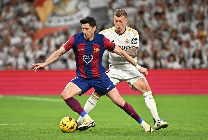 Barcelonas Polish forward #09 Robert Lewandowski vies with Real Madrids German midfielder #08 Toni Kroos during the Spanish league football match between Real Madrid CF and FC Barcelona at the Santiago Bernabeu stadium in Madrid on April 21, 2024. (Photo by JAVIER SORIANO / AFP)
