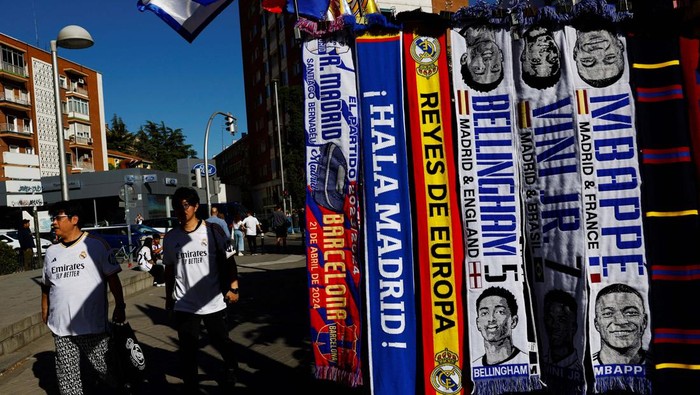 A vendor stands next to football scarves of French player Kylian Mbappe and other Real Madrid players, outside Real Madrid’s Santiago Bernabeu stadium in Madrid, Spain, May 8, 2024. REUTERS/Susana Vera