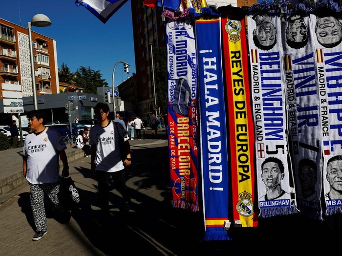A vendor stands next to football scarves of French player Kylian Mbappe and other Real Madrid players, outside Real Madrid’s Santiago Bernabeu stadium in Madrid, Spain, May 8, 2024. REUTERS/Susana Vera