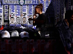 Penggemar Real Madrid berjalan melewati stand yang menjual syal sepakbola bergambar Jude Bellingham, Vinicius Junior dan Kylian Mbappe, di luar stadion Santiago Bernabeu Real Madrid di Madrid, Spanyol, 21 April 2024. REUTERS/Susana Vera. 
