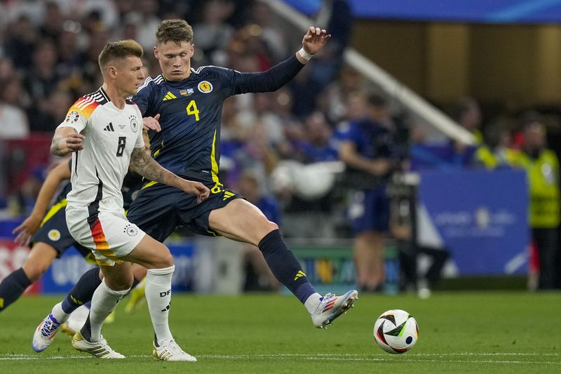 Scotland's Scott McTominay, right, duels for the ball with Germany's Toni Kroos during a Group A match between Germany and Scotland at the Euro 2024 soccer tournament in Munich, Germany, Friday, June 14, 2024. (AP Photo/Antonio Calanni)
