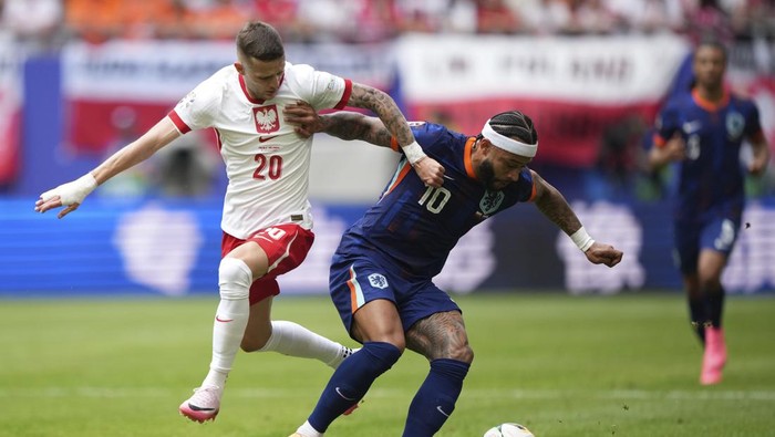 Polands Sebastian Szymanski, left, challenges for the ball with Memphis Depay of the Netherlands during the Group D match between Poland and the Netherlands at the Euro 2024 soccer tournament in Hamburg, Germany, Sunday, June 16, 2024. (AP Photo/Ebrahim Noroozi)