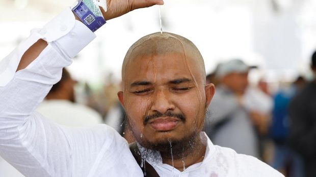 Seorang peziarah Muslim menuangkan air ke kepalanya untuk mendinginkan diri dari panas, saat ia mengikuti ibadah haji tahunan di Mina, Arab Saudi, 17 Juni 2024. REUTERS/Mohammed Torokman
