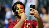 Tak lengkap rasanya bila face paint yang nyentrik tidak diabadikan. Ya, itu yang dilakukan seorang suporter Belgia yang terlihat asyik swafoto. REUTERS/Kai Pfaffenbach