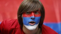 Dengan gaya rambut jadul ditambah riasan cat diwajahnya, suporter Serbia ini terlihat sangat nyentrik. REUTERS/John Sibley