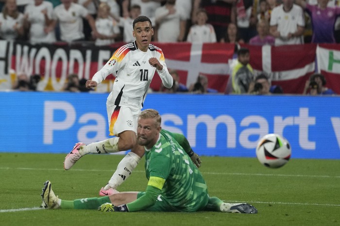 Germanys Jamal Musiala, top, scores his sides 2nd goal against Denmarks goalkeeper Kasper Schmeichel during a round of sixteen match at the Euro 2024 soccer tournament in Dortmund, Germany, Saturday, June 29, 2024. (AP Photo/Darko Vojinovic)