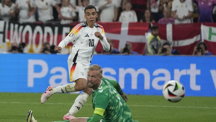 Germanys Jamal Musiala, top, scores his sides 2nd goal against Denmarks goalkeeper Kasper Schmeichel during a round of sixteen match at the Euro 2024 soccer tournament in Dortmund, Germany, Saturday, June 29, 2024. (AP Photo/Darko Vojinovic)