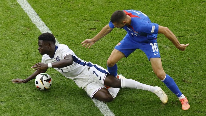 Soccer Football - Euro 2024 - Round of 16 - England v Slovakia - Arena AufSchalke, Gelsenkirchen, Germany - June 30, 2024 Englands Bukayo Saka in action with Slovakias David Hancko REUTERS/Leon Kuegeler