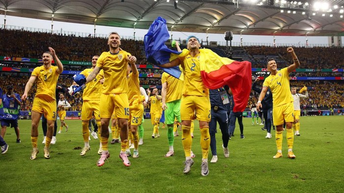 FRANKFURT AM MAIN, GERMANY - JUNE 26: Denis Dragus and Andrei Ratiu of Romania celebrate with a Romania national flag after the teams qualification to the knockout stages following the UEFA EURO 2024 group stage match between Slovakia and Romania at Frankfurt Arena on June 26, 2024 in Frankfurt am Main, Germany. (Photo by Ryan Pierse - UEFA/UEFA via Getty Images)