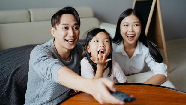 Two generation Asian family relaxing at home and watching TV shows together
