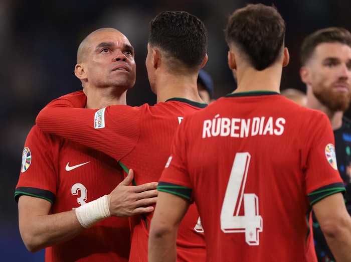 HAMBURG, GERMANY - JULY 05: Ruben Dias of Portugal looks on as Cristiano Ronaldo embraces an emotional Pepe following the penalty shoot out defeat in the UEFA EURO 2024 quarter-final match between Portugal and France at Volksparkstadion on July 05, 2024 in Hamburg, Germany. (Photo by Jonathan Moscrop/Getty Images)