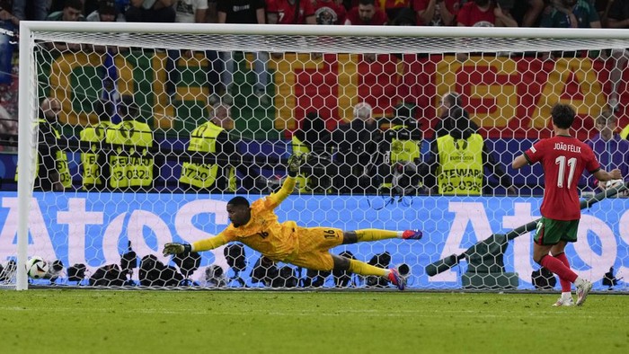 Mike Maignan, Joao Felix Portugal's Joao Felix, right, hits the goal post and misses a shot during a shootout in a quarter final match between Portugal and France at the Euro 2024 soccer tournament in Hamburg, Germany, Friday, July 5, 2024. France goalkeeper Mike Maignan is center. (AP Photo/Frank Augstein)