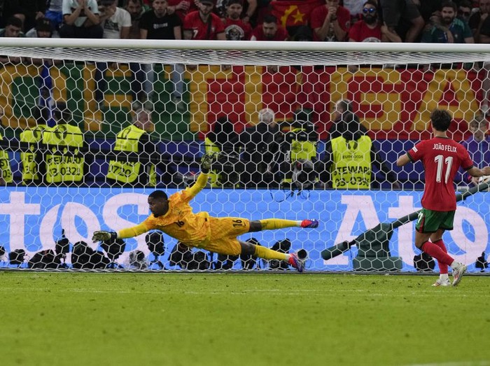 Portugal's Joao Felix, right, hits the goal post and misses a shot during a shootout in a quarter final match between Portugal and France at the Euro 2024 soccer tournament in Hamburg, Germany, Friday, July 5, 2024. France goalkeeper Mike Maignan is center. (AP Photo/Frank Augstein)