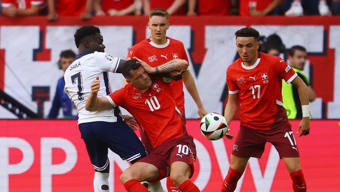 Soccer Football - Euro 2024 - Quarter Final - England v Switzerland - Dusseldorf Arena, Dusseldorf, Germany - July 6, 2024 Englands Bukayo Saka in action with Switzerlands Granit Xhaka and Ruben Vargas REUTERS/Kai Pfaffenbach