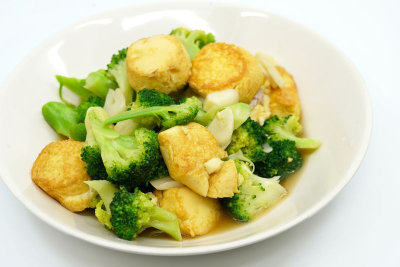 Thai food, Stir-fried broccoli and deep-fried Egg-Tofu with oyster sauce. Healthy food image on white background, view side and above a 45-degree angle.