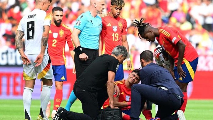 Soccer Football - Euro 2024 - Quarter Final - Spain v Germany - Stuttgart Arena, Stuttgart, Germany - July 5, 2024 Spains Pedri receives medical attention after sustaining an injury as Germanys Toni Kroos, Spains Nico Williams and referee Anthony Taylor look on REUTERS/Angelika Warmuth