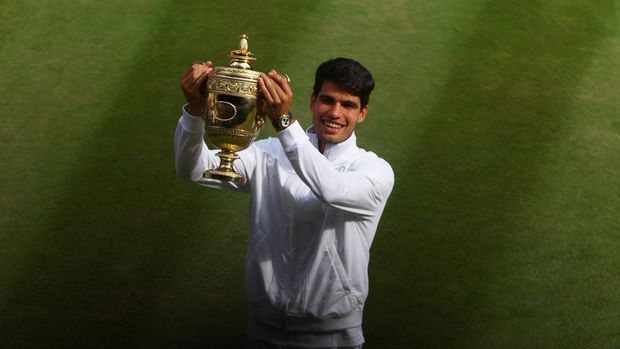 Tennis - Wimbledon - All England Lawn Tennis and Croquet Club, London, Britain - July 14, 2024 Spain's Carlos Alcaraz celebrates with the trophy after winning the men's singles final against Serbia's Novak Djokovic REUTERS/Matthew Childs