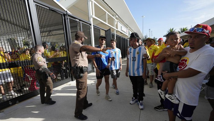 Policemen give instructions to fans outside the stadium prior to the Copa America final soccer match between Argentina and Colombia Sunday, July 14, 2024, in Miami Gardens, Fla. (AP Photo/Lynne Sladky)