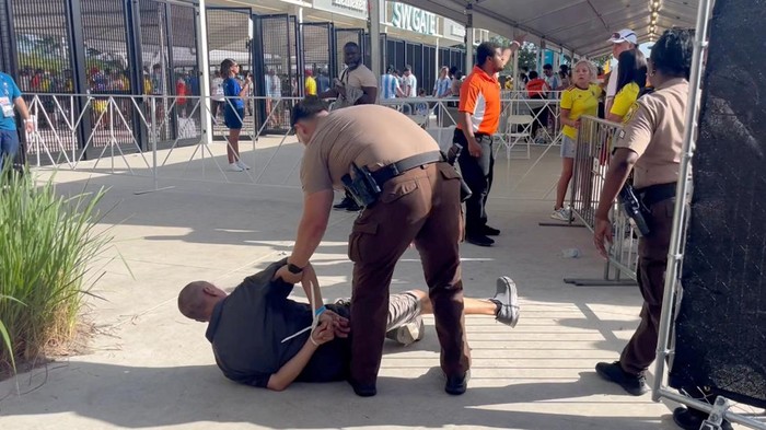 A man is detained by the police, amid reports of fans rushing the gates before the final match of Copa America between Argentina and Colombia at Hard Rock Stadium, in Miami, Florida, U.S., July 14, 2024, in this screengrab obtained from a social media video. sammbonu/via REUTERS  THIS IMAGE HAS BEEN SUPPLIED BY A THIRD PARTY. MANDATORY CREDIT. NO RESALES. NO ARCHIVES.