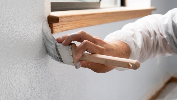 Man painting interior of home in gray paint