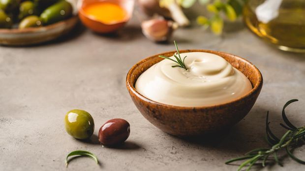 Bowl of Homemade mayonnaise sauce with olives, ingredients and herbs for cooking