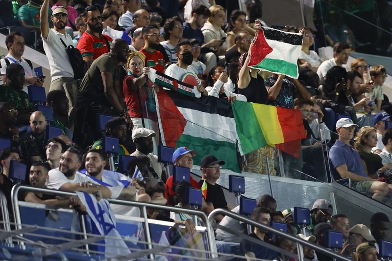 Spectators hold Palestinian flags as they watch the men's group D match between Israel and Mali at the Parc des Princes during the 2024 Summer Olympics, Wednesday, July 24, 2024, in Paris, France. (AP Photo/Aurelien Morissard)