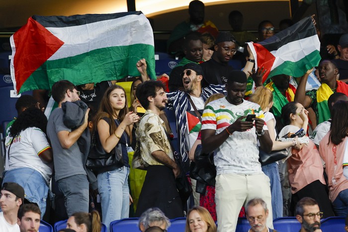 Spectators hold Palestinian flags as they watch the mens group D match between Israel and Mali at the Parc des Princes during the 2024 Summer Olympics, Wednesday, July 24, 2024, in Paris, France. (AP Photo/Aurelien Morissard)