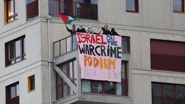 Paris 2024 Olympics - Opening Ceremony - Paris, France - July 26, 2024. Spectators with a Palestine flag display a banner criticising Israel from a balcony amid the ongoing conflict between Israel and Hamas during the opening ceremony. Pool via REUTERS/Nir Elias