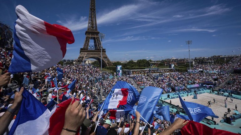Pendukung Prancis mengibarkan bendera selama pertandingan voli pantai grup C putri antara Jerman dan Prancis di Stadion Menara Eiffel. AP/Louise Delmotte