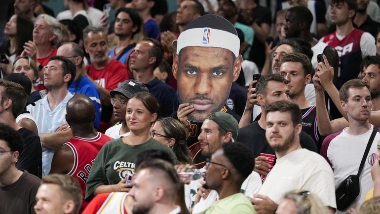 Para penggemar Amerika Serikat bersorak, saat salah satu dari mereka memegang potongan gambar LeBron James, sebelum pertandingan basket putra antara Amerika Serikat dan Sudan Selatan dimulai di Olimpiade Musim Panas 2024. AP/Mark J. Terrill