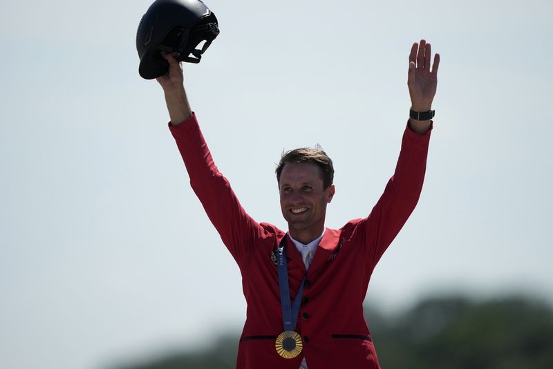 Germany's Christian Kukuk celebrates with his gold medal after winning the Jumping Individual final at the 2024 Summer Olympics, Tuesday, Aug. 6, 2024, in Versailles, France. (AP Photo/Mosa'ab Elshamy)